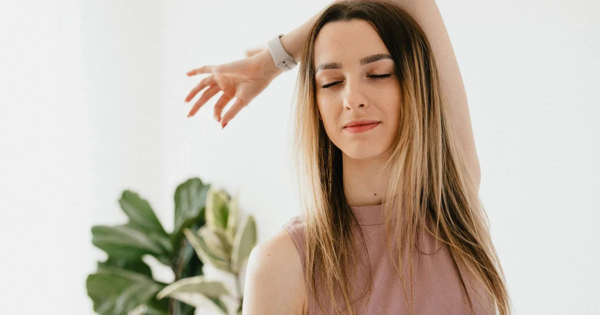 Nő csukott szemmel, nyugodtan lélegzik egy világos szobában, 5 perces reggeli meditáció